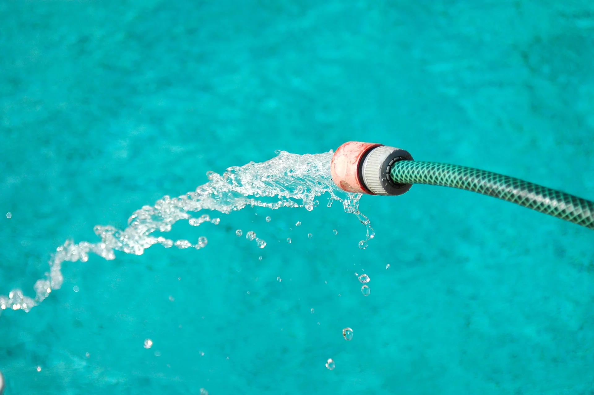 Close up on a hose pumping water into an above-ground pool.